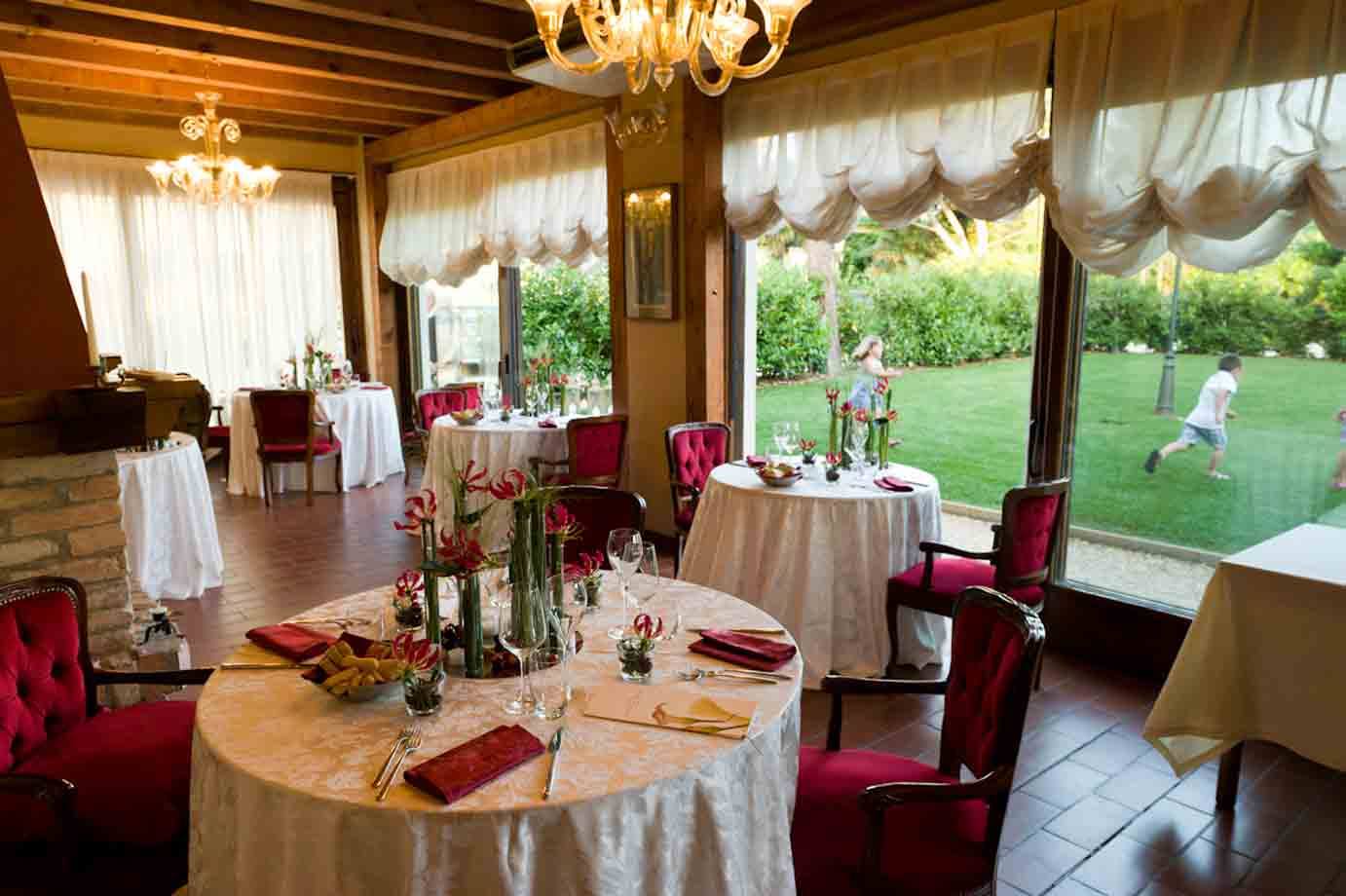 Sala ristorante con tavoli apparecchiati, sedie rosse e Murano a gocce