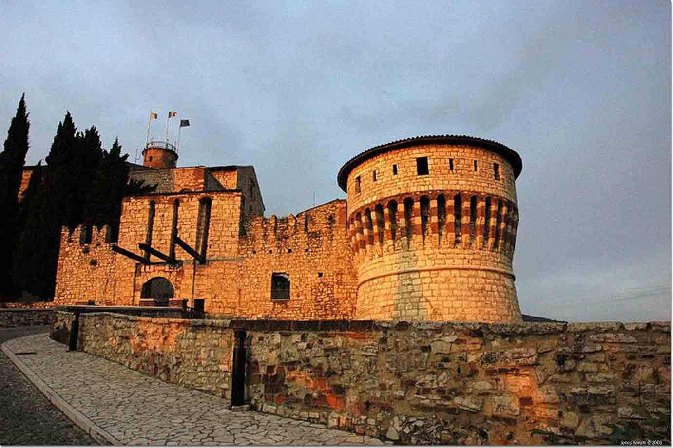 Castello di Brescia: torre rotonda in pietra illuminata dal sole al crepuscolo