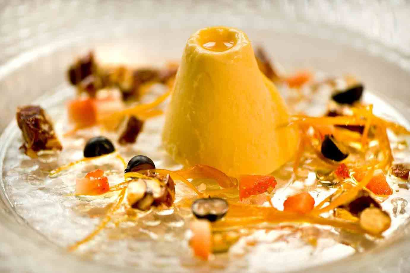 Dessert giallo a forma di cono su gelatina con frutta e scorze d'arancia