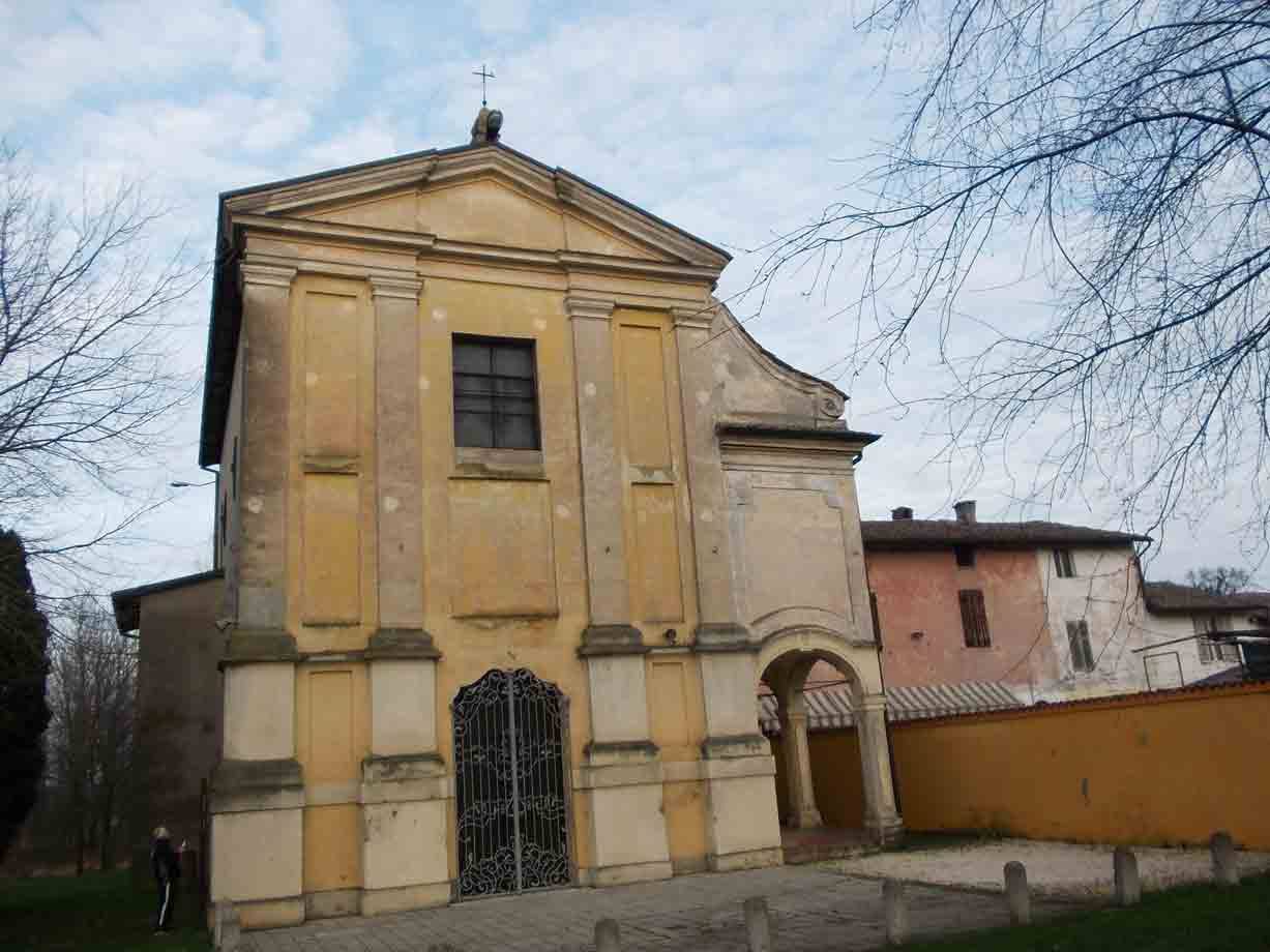 Chiesa gialla ocra con portale in ferro battuto e cielo nuvoloso
