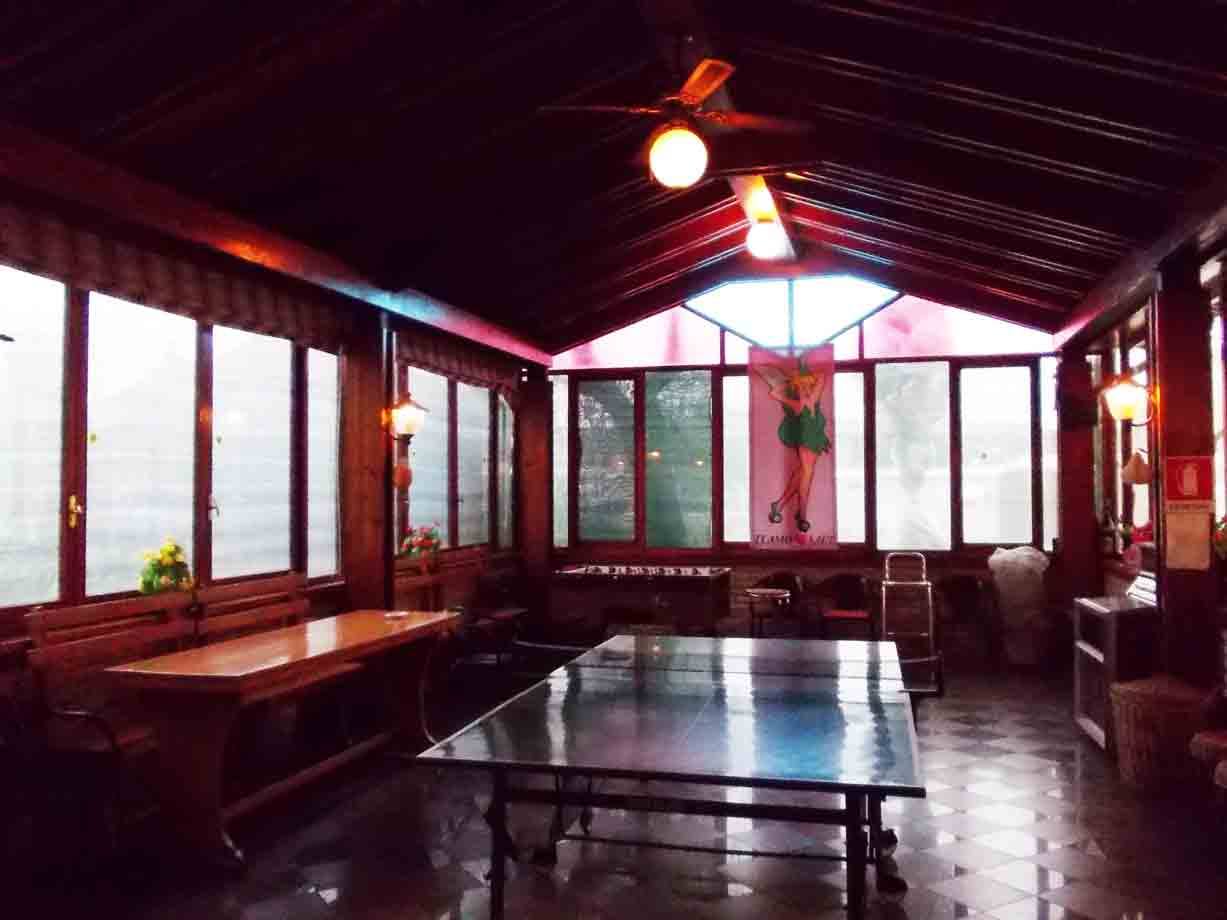 Sala in legno con tavolo da ping-pong, lampadari accesi e finestre illuminate