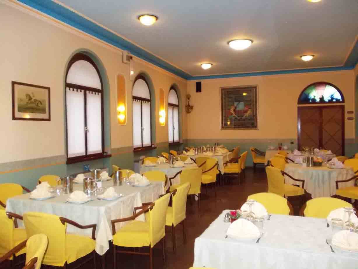 Sala ristorante con tavoli apparecchiati a tovaglia bianca e sedie gialle