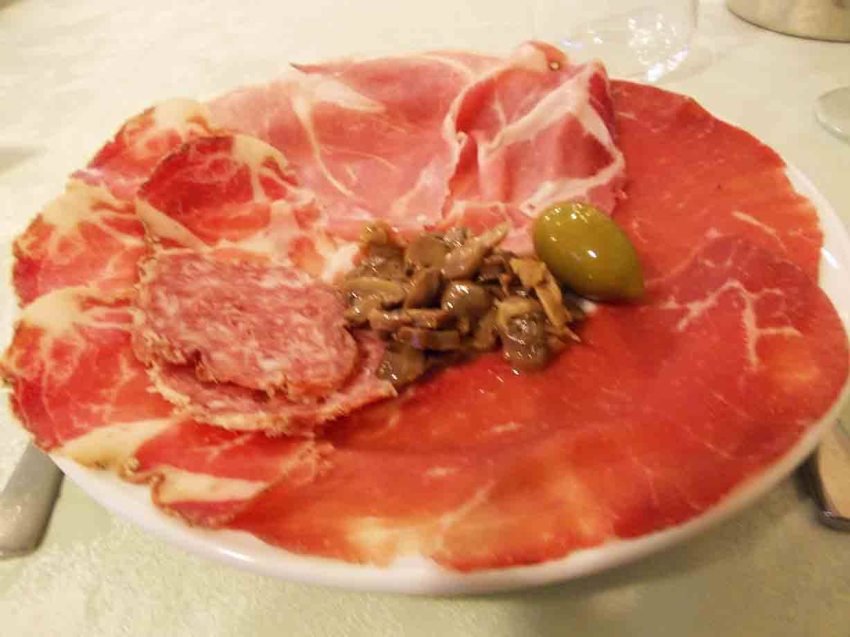 Piatto di affettati: prosciutto crudo, salame, funghi e un'oliva