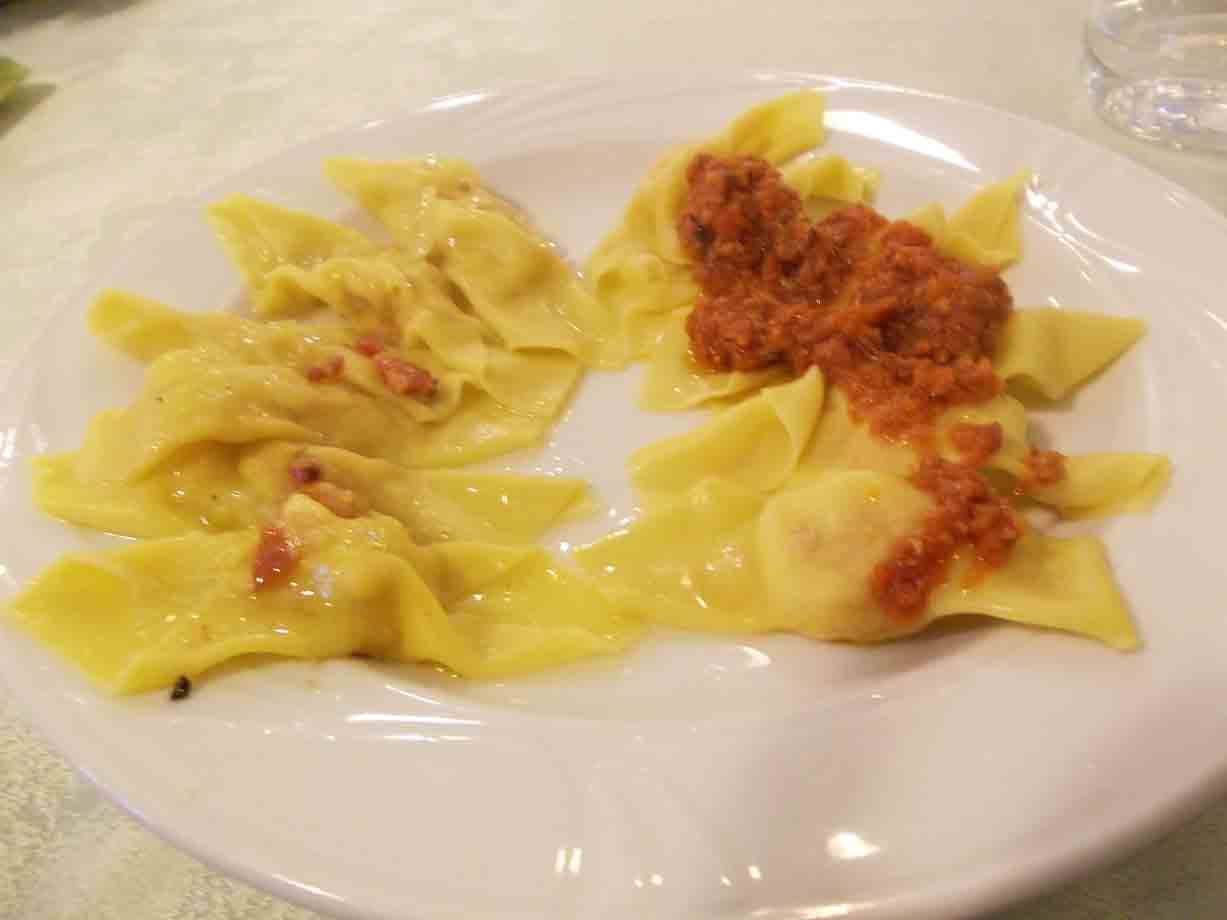 Piatto bianco con ravioli al burro e ragù, luce da interno