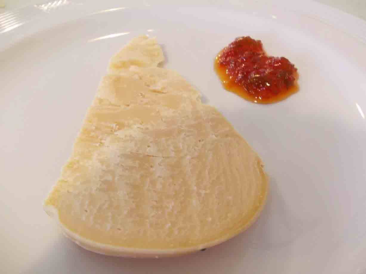 Fetta di formaggio con confettura piccante su piatto bianco