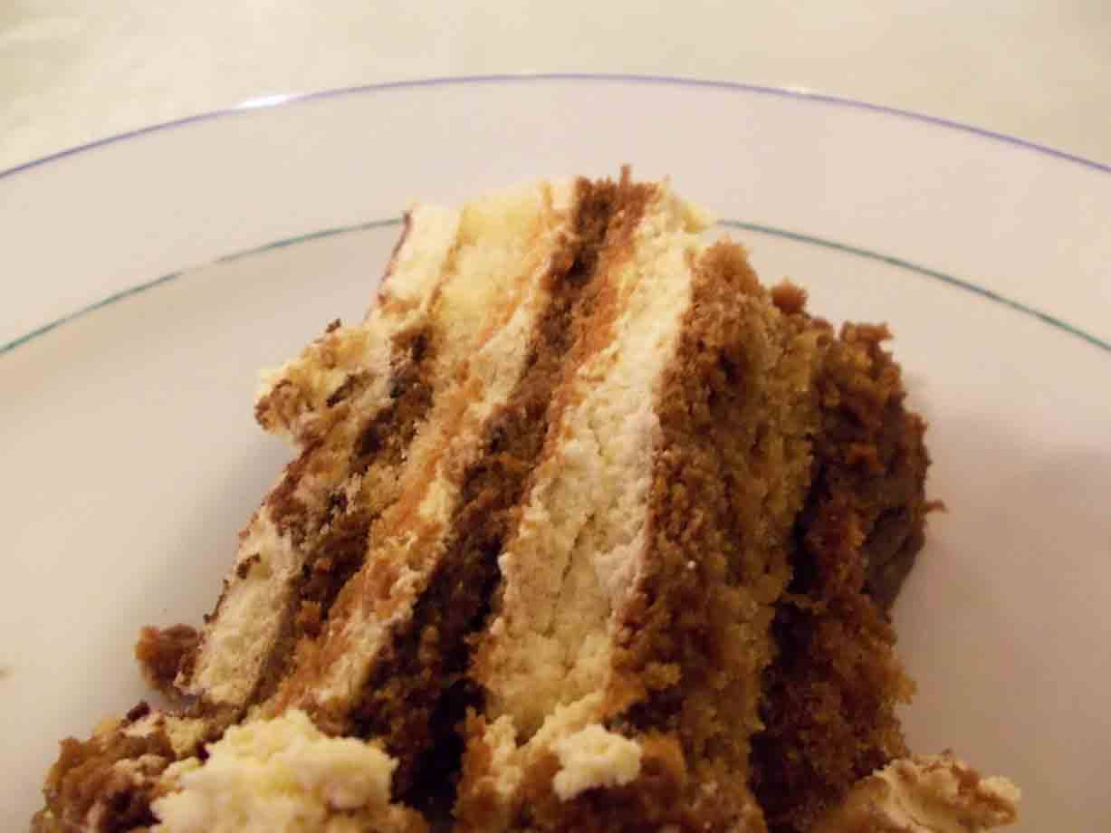 Fetta di tiramisù con strati di crema e savoiardi, su piatto bianco