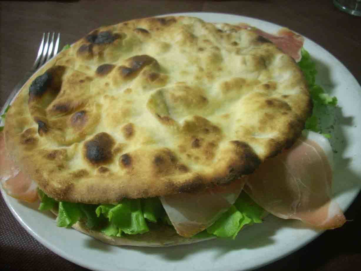 Focaccia ripiena di prosciutto e lattuga su piatto bianco