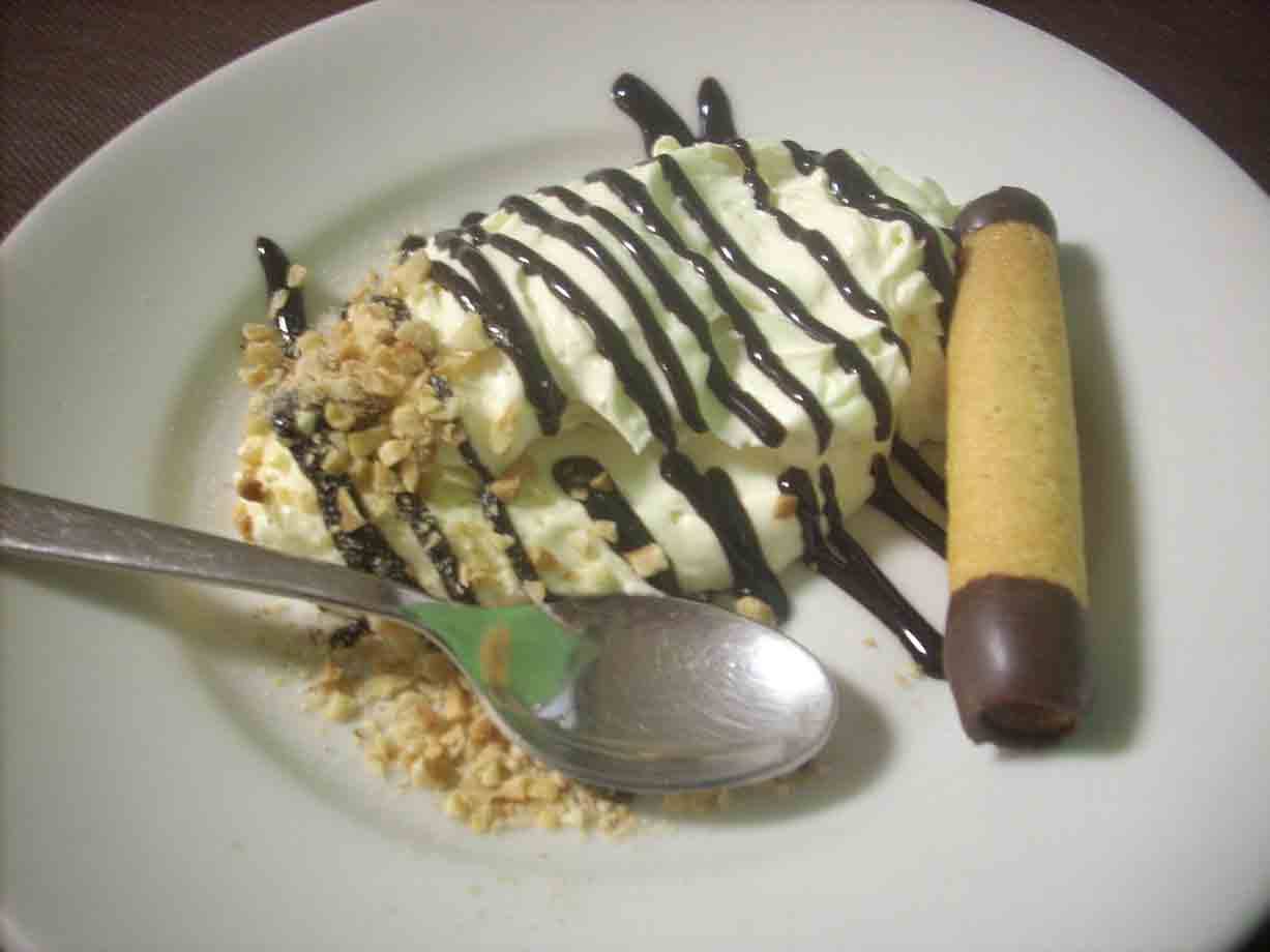 Dessert con crema, cioccolato fondente e wafer su piatto bianco, luci artificiali