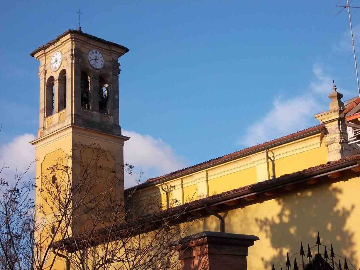 Campanile con orologio e chiesa gialla sotto cielo azzurro