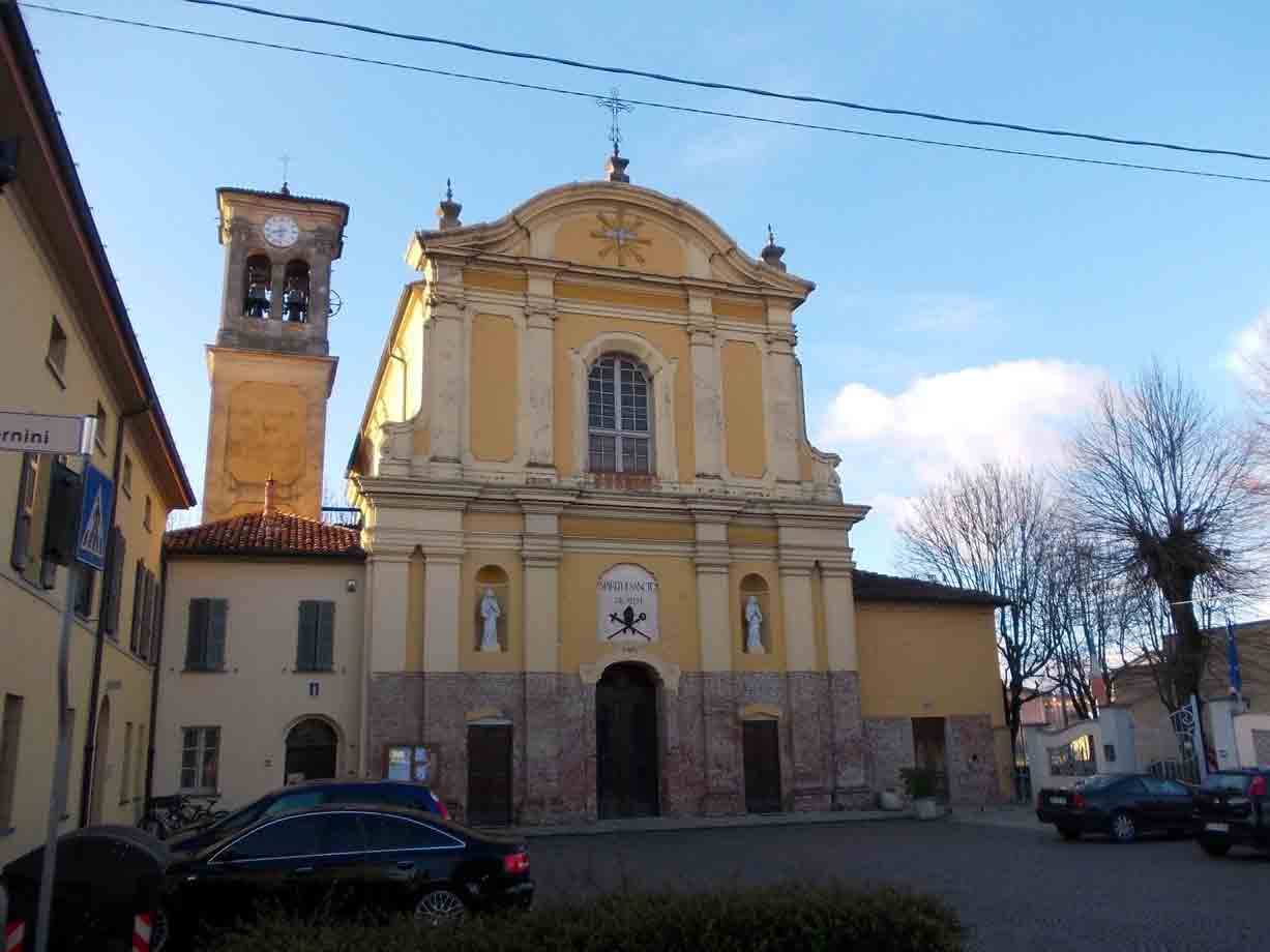 Chiesa gialla con facciata barocca e campanile, auto parcheggiate nella piazza