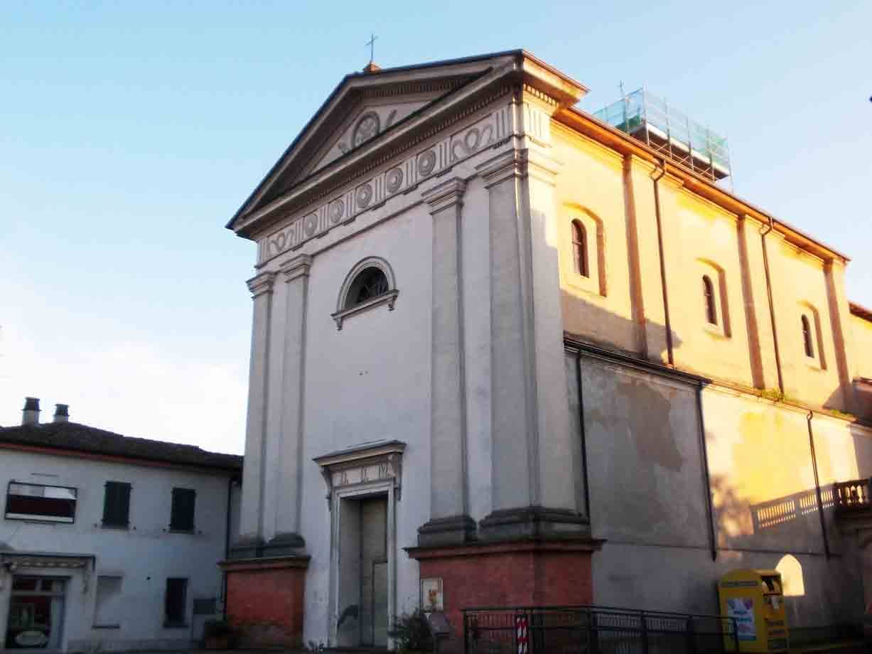 Chiesa con facciata bianca e timpano, impalcature sul tetto, luce pomeridiana