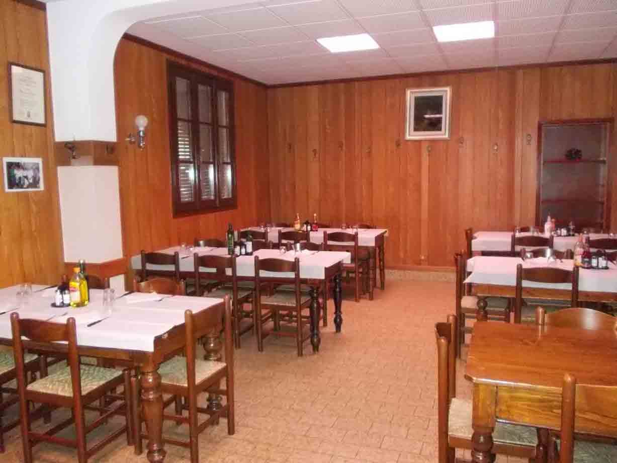 Sala da pranzo vuota con tavoli in legno, tovaglie bianche e pareti in legno