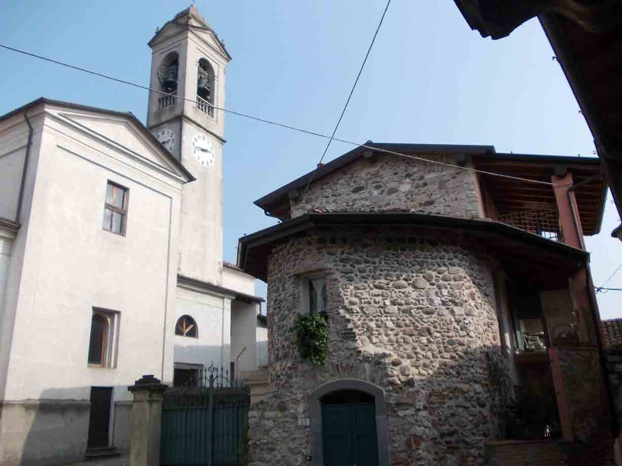 Campanile con orologio accanto a casa in pietra a vista, luce diurna