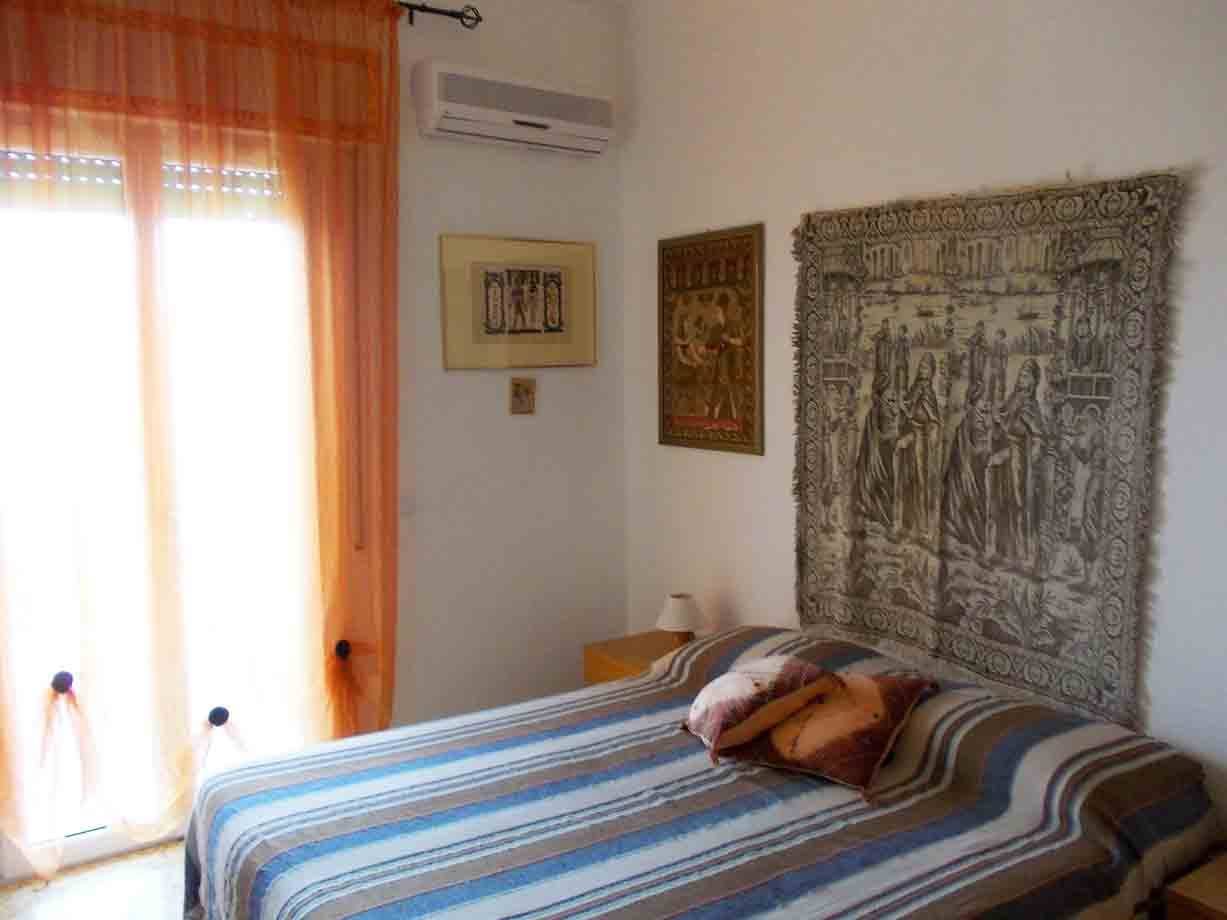 Camera da letto con letto a strisce, arazzo medievale appeso al muro e aria condizionata