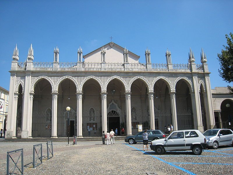 Facciata bianca del Duomo di Biella con archi e guglie sotto il cielo azzurro