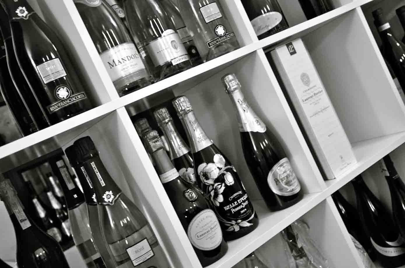 Bottiglie di champagne e spumante in bianco e nero su scaffali bianchi