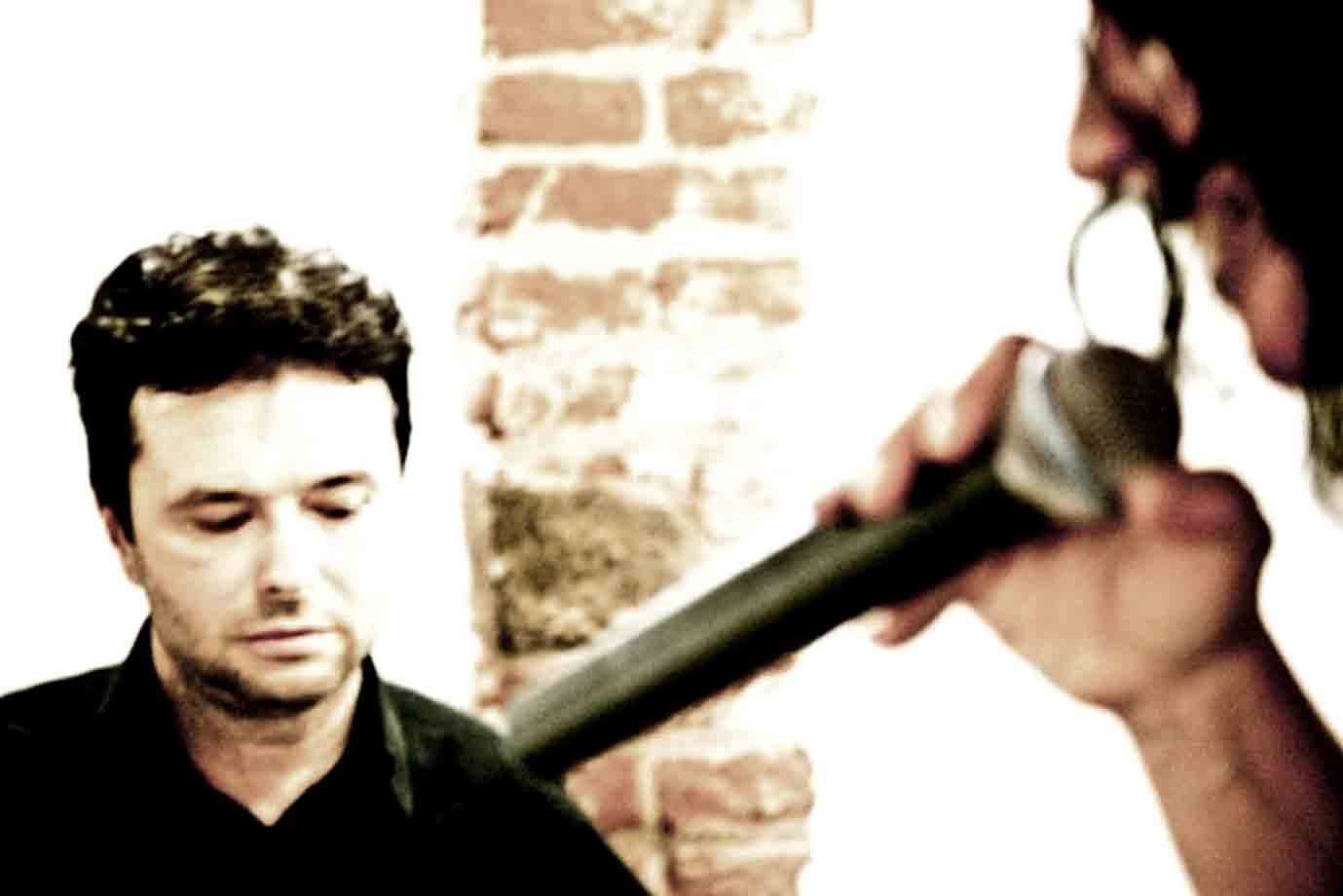uomo in nero con occhi chiusi accanto a una mano che regge un microfono