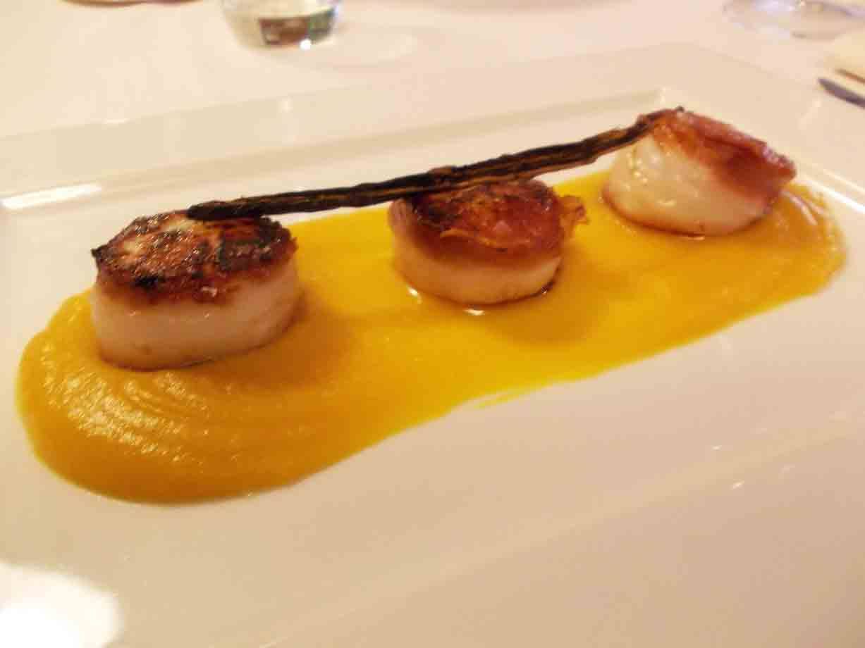 Capesante scottate su crema di zucca, piatto bianco in ristorante