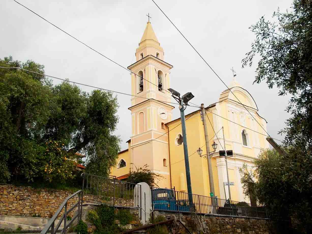 Chiesa gialla con campanile tra alberi e cavi elettrici, cielo grigio