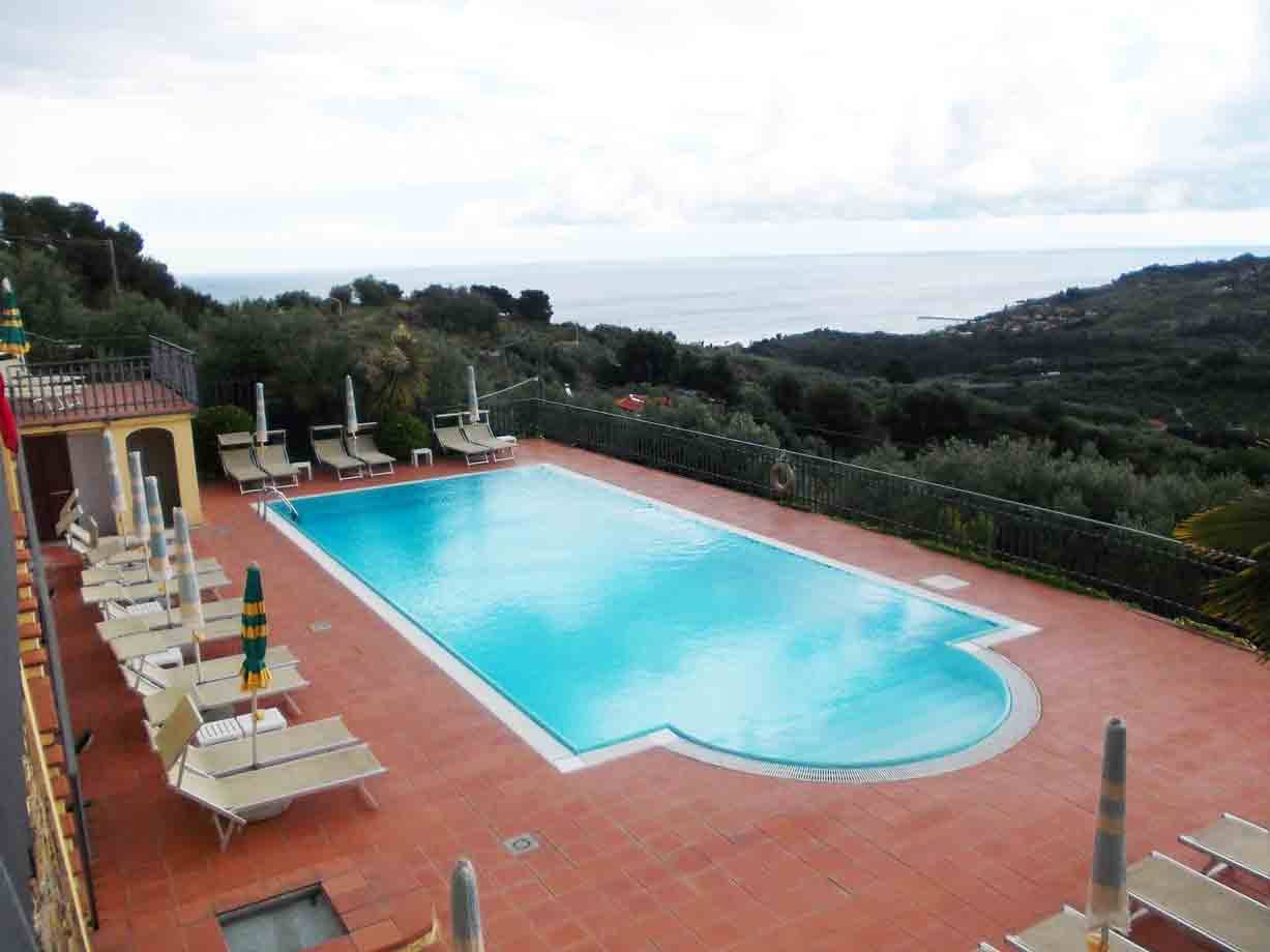 Piscina con sdraio e ombrelloni su terrazza sopra il mare
