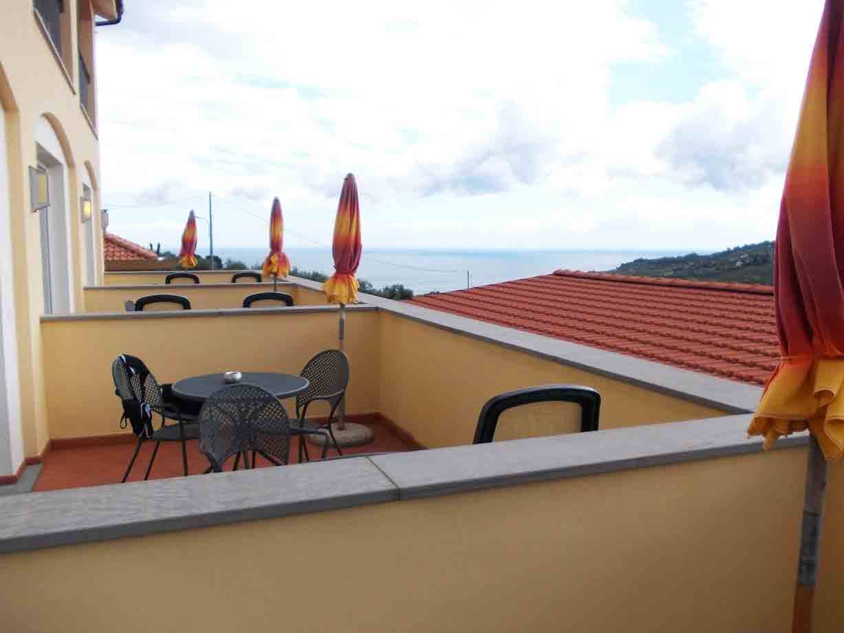 Terrazza con tavoli metallici e ombrelloni chiusi davanti al mare