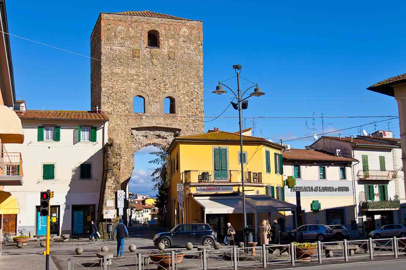 Antica torre in pietra con arco sopra le case colorate della piazza