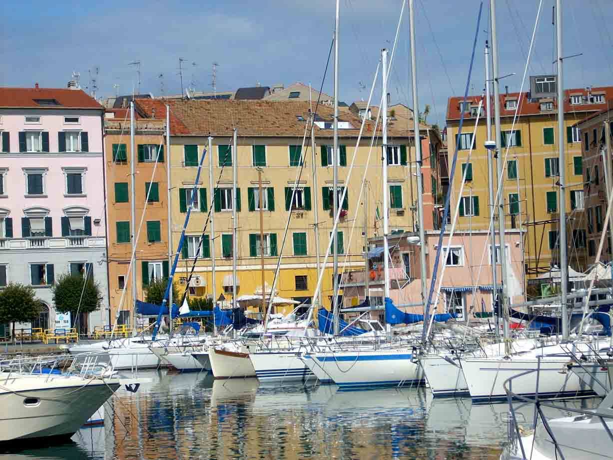 Vele alberate in porto davanti a case colorate con persiane verdi