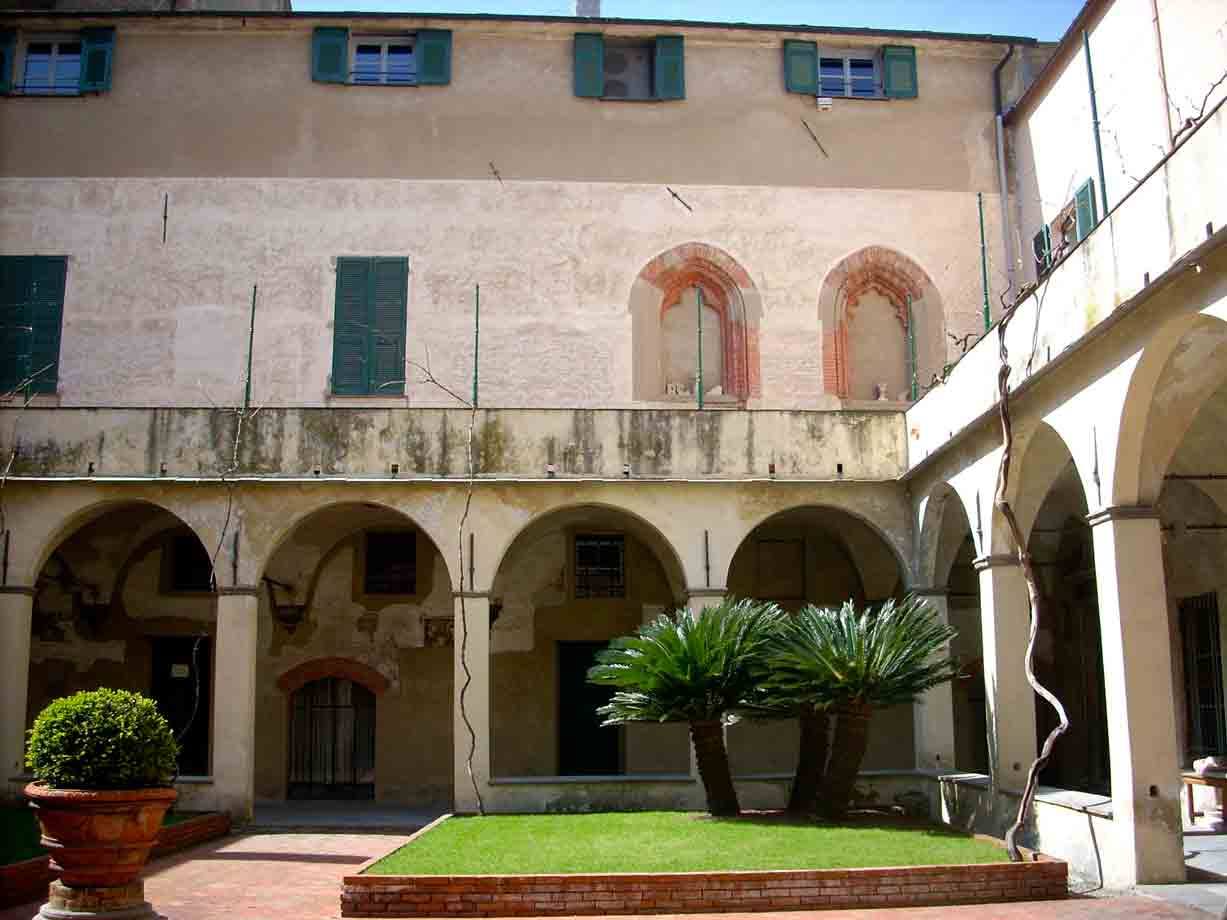Chiostro con arcate, cicadi e prato al centro, pareti affrescate sbiadite