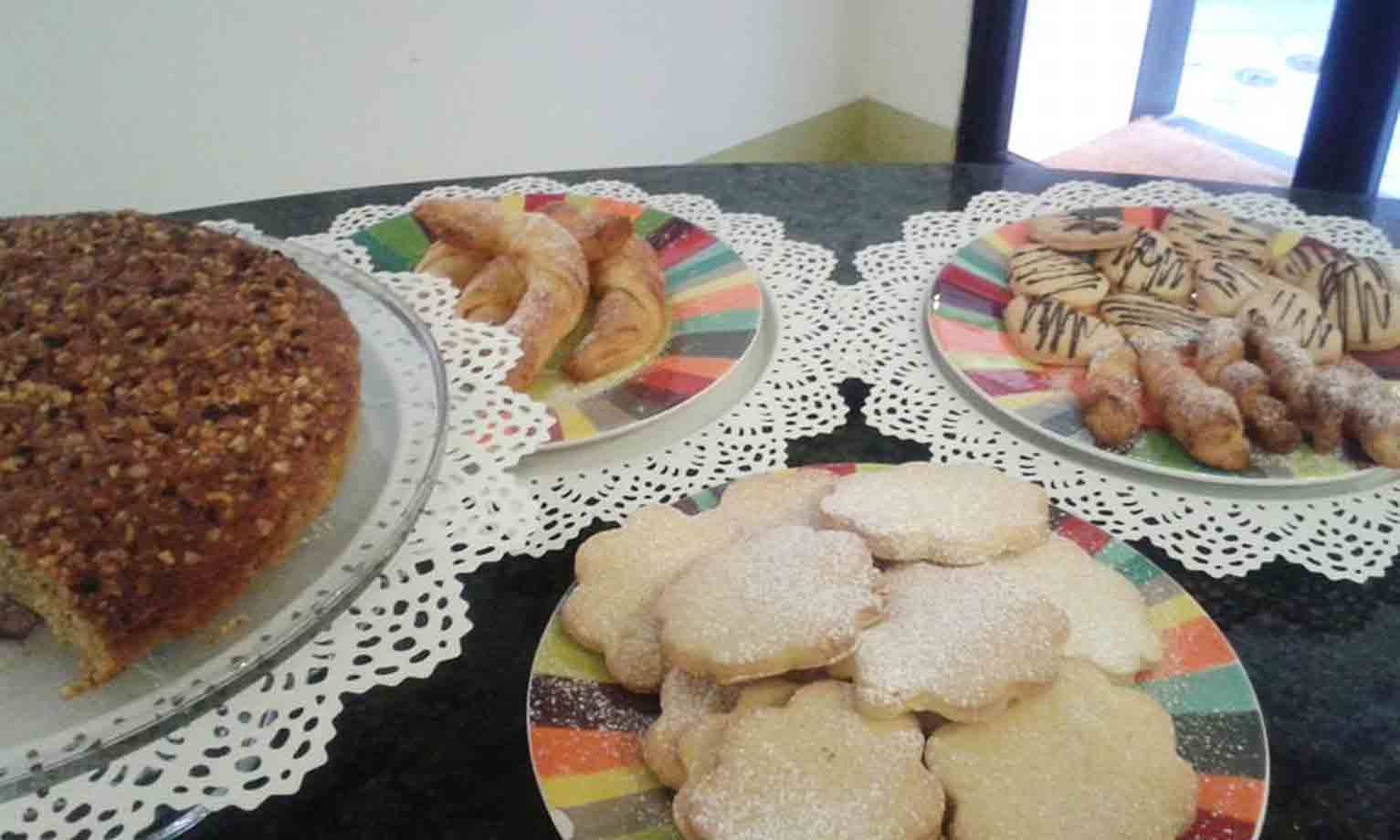Torta alle noci, cornetti e biscotti su piatti colorati con centrini di carta
