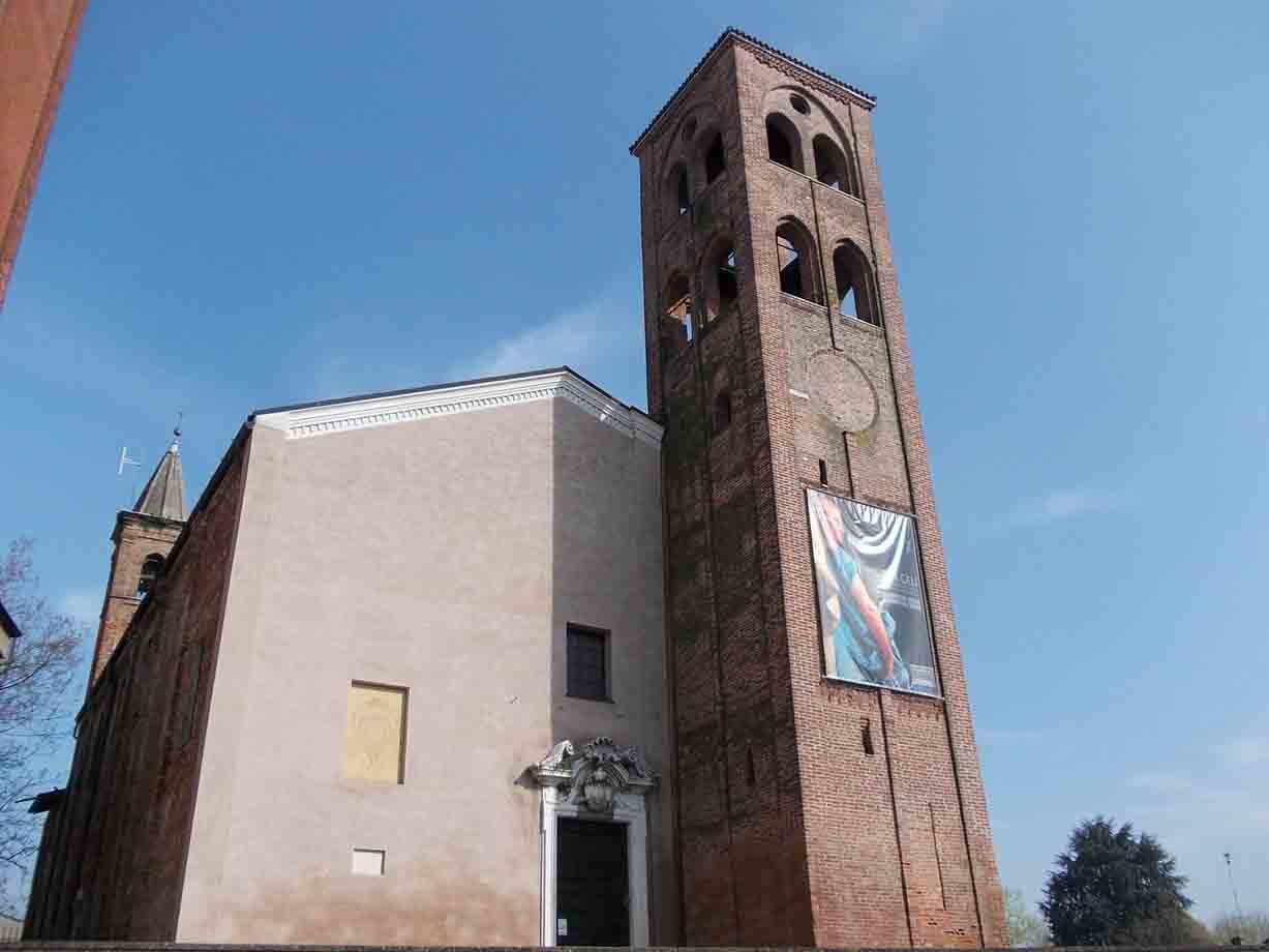 Chiesa in mattoni con campanile romanico sotto cielo azzurro