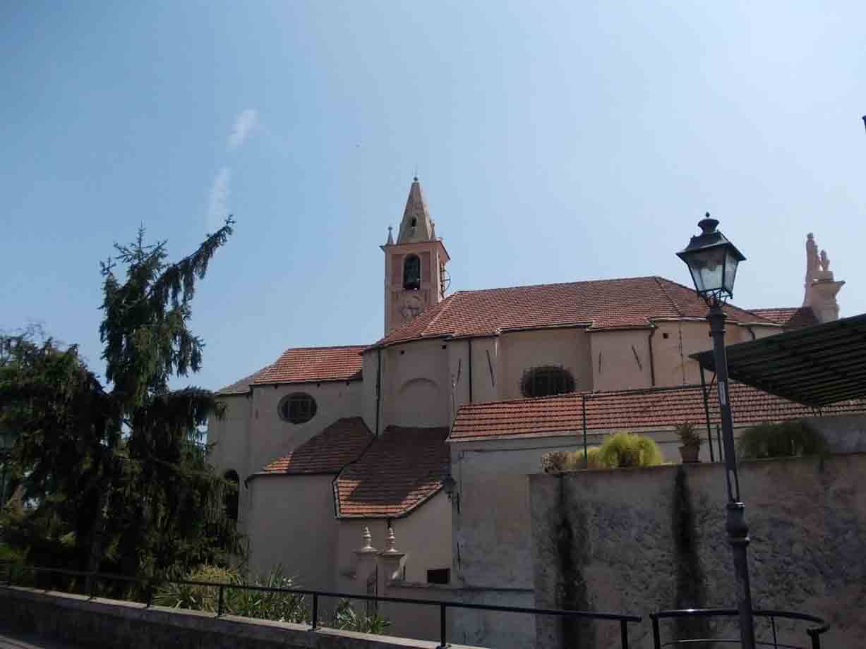 Chiesa con campanile e tetti di terracotta, cielo azzurro, lampione in primo piano