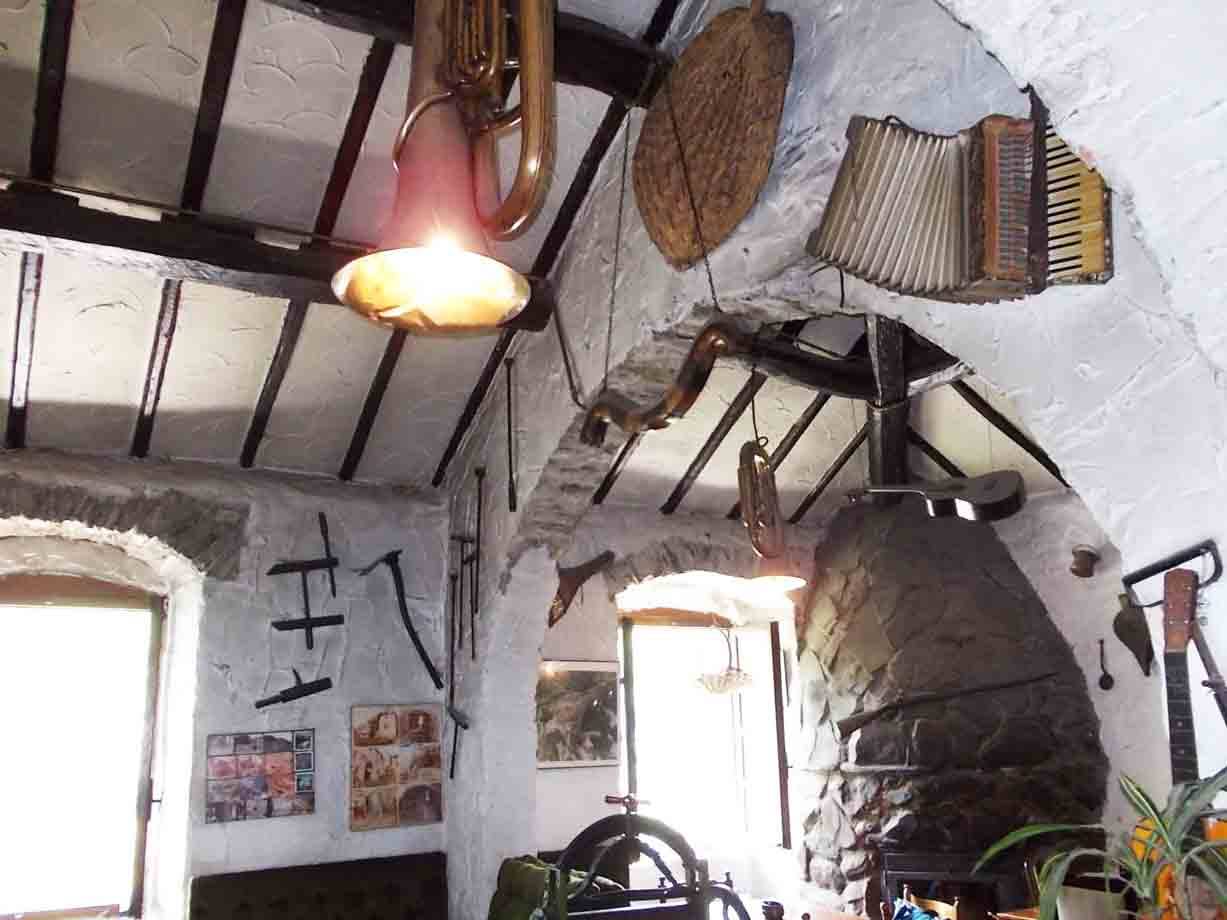 Tubo e fisarmonica appesi alle travi di legno sopra un camino di pietra