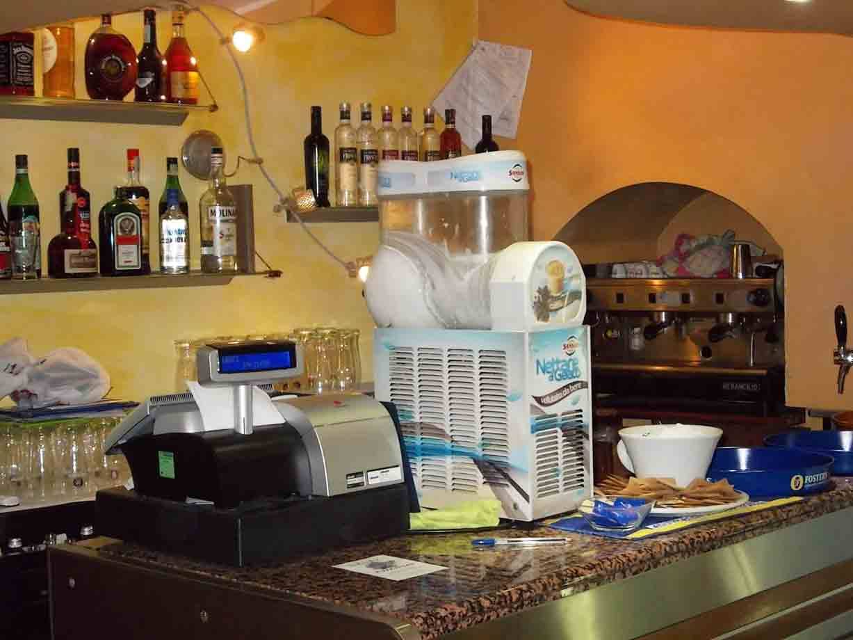 Bancone del bar con cassa, macchina del granita, bottiglie e macchina caffè