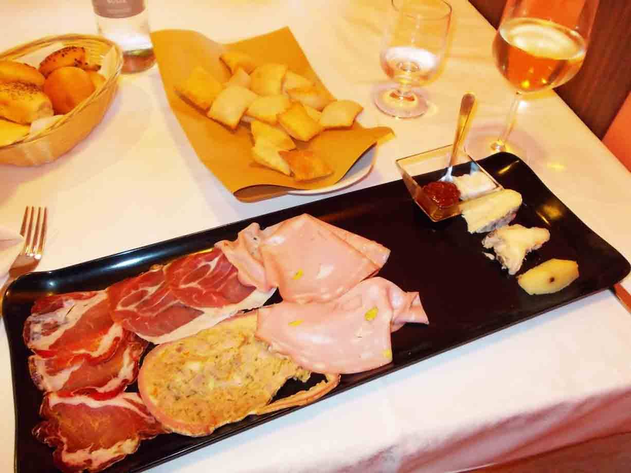Vassoio nero con salumi, formaggi e crescentine, calice di vino bianco