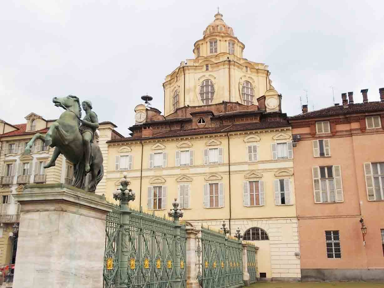 Statua equestre in bronzo davanti alle cancellate verdi di Palazzo Reale a Torino