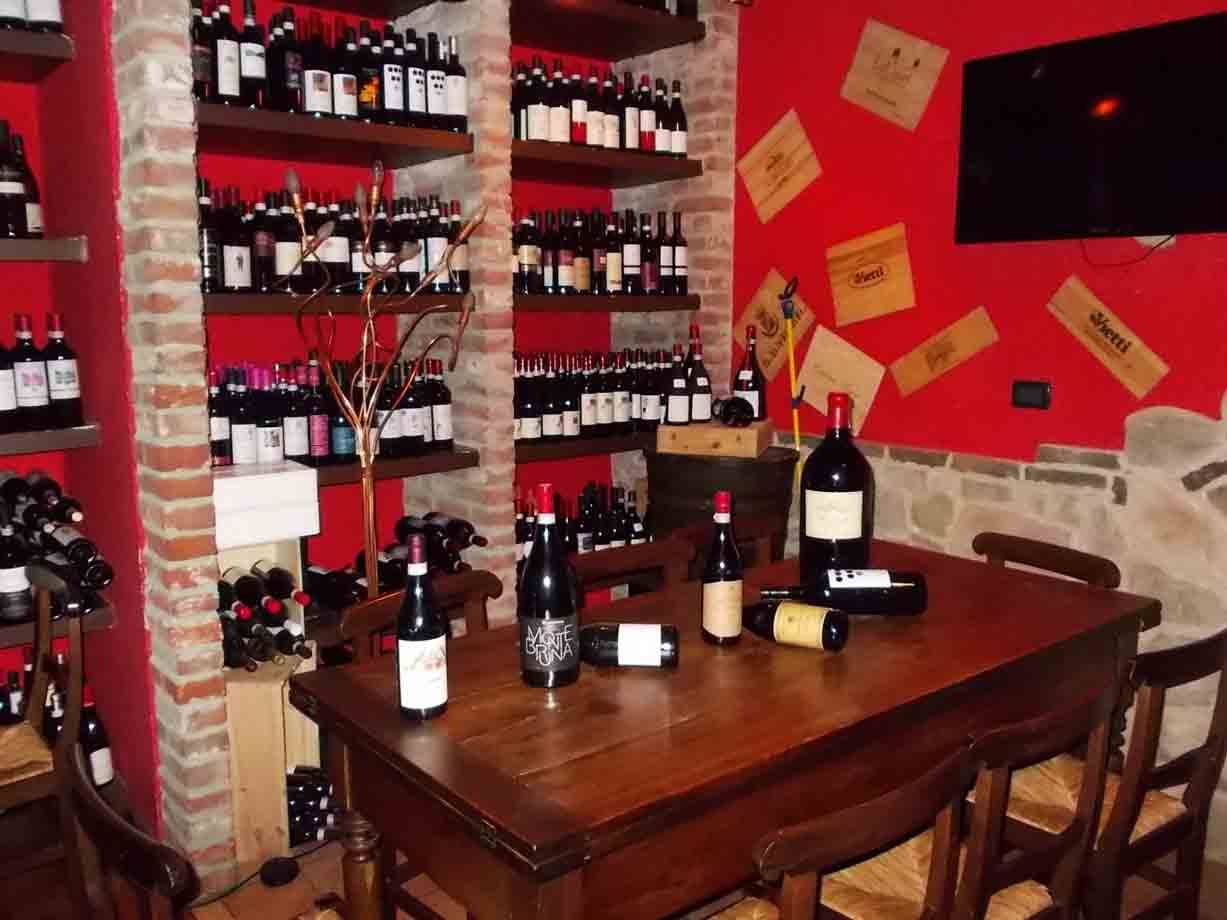 Bottiglie di vino su tavolo in legno e scaffali in muratura di mattoni, parete rossa