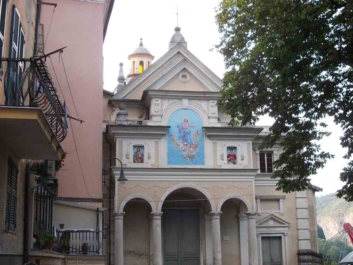 Chiesa barocca con affresco azzurro sulla facciata, archi e campanile tra gli alberi