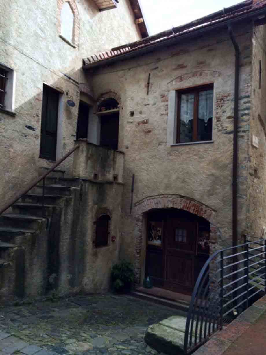 Scala esterna in pietra su casa medievale con portale ad arco