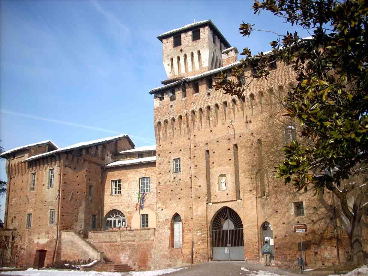 Castello in mattoni con torre merlata e portale ad arco, neve a terra