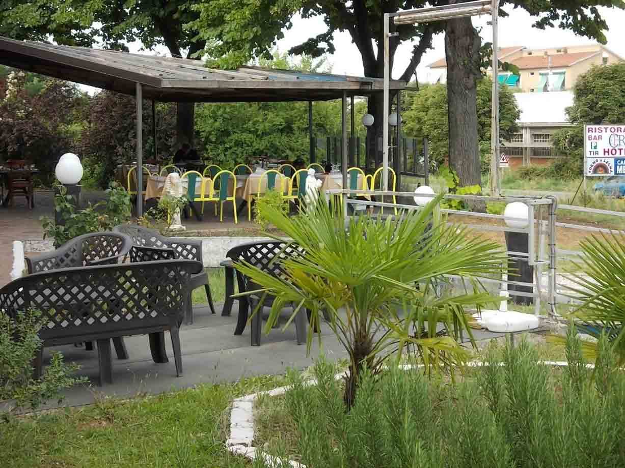 Sedie nere e palma nel giardino di un ristorante con tavoli apparecchiati sotto il gazebo