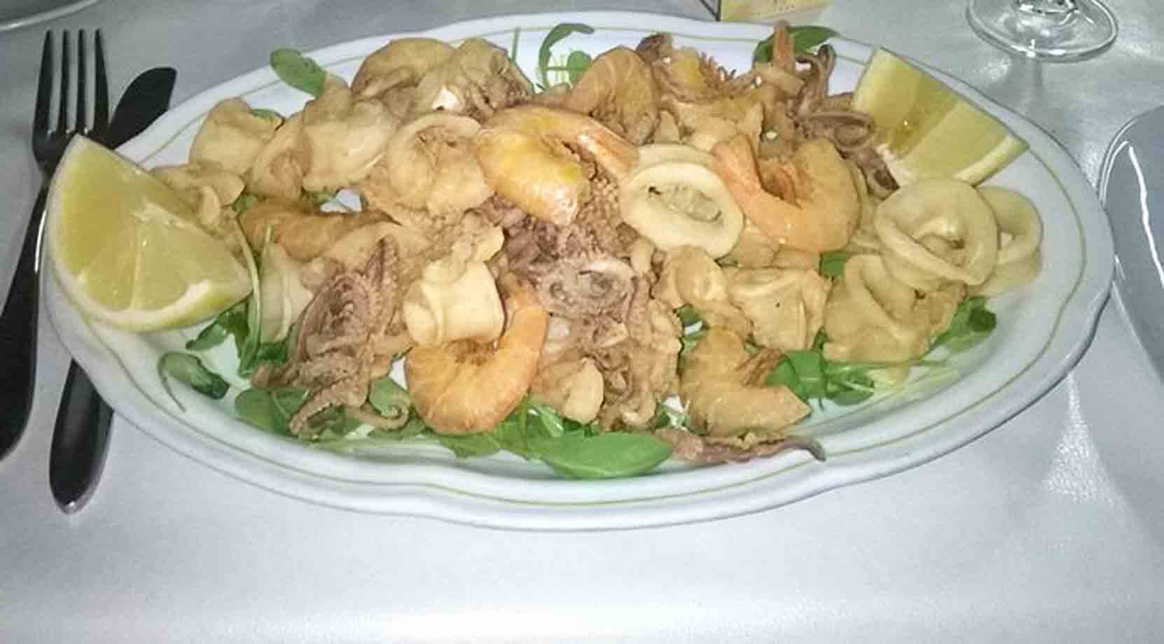 Piatto di fritto misto di calamari e gamberi con limone e rucola