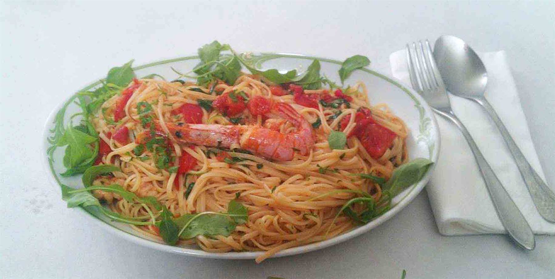 Piatto di spaghetti al pomodoro con gamberone e rucola fresca
