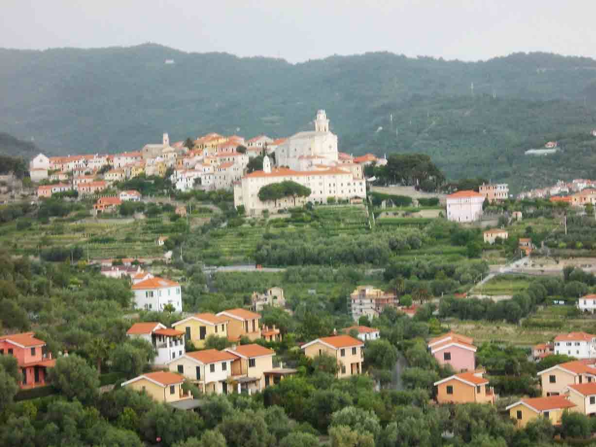 Borgo con case colorate e chiesa tra colline coltivate e uliveti