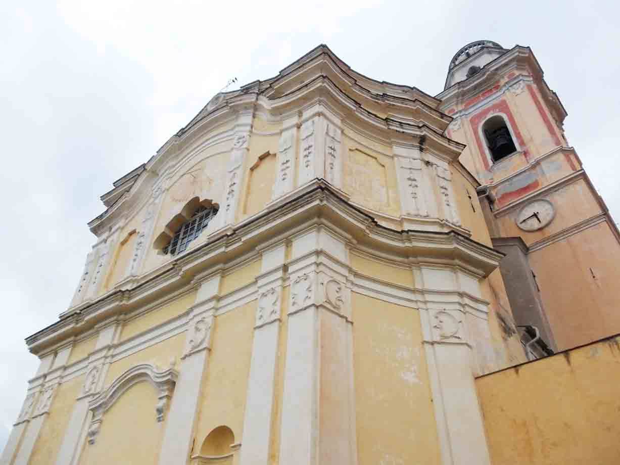 Chiesa barocca gialla con campanile ocra e orologio, cielo grigio