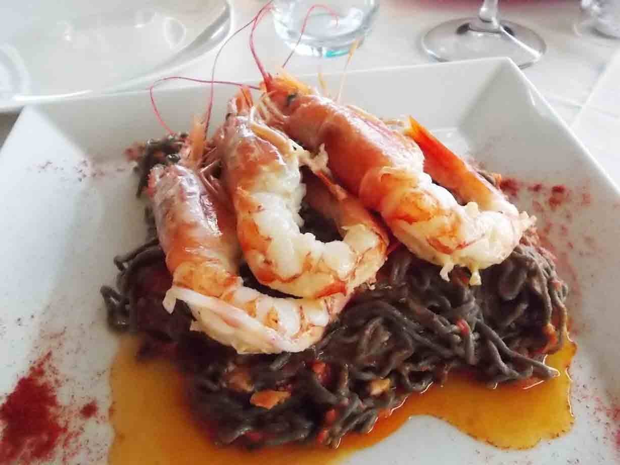 Piatto bianco con spaghetti al nero di seppia e grandi gamberi, luce naturale