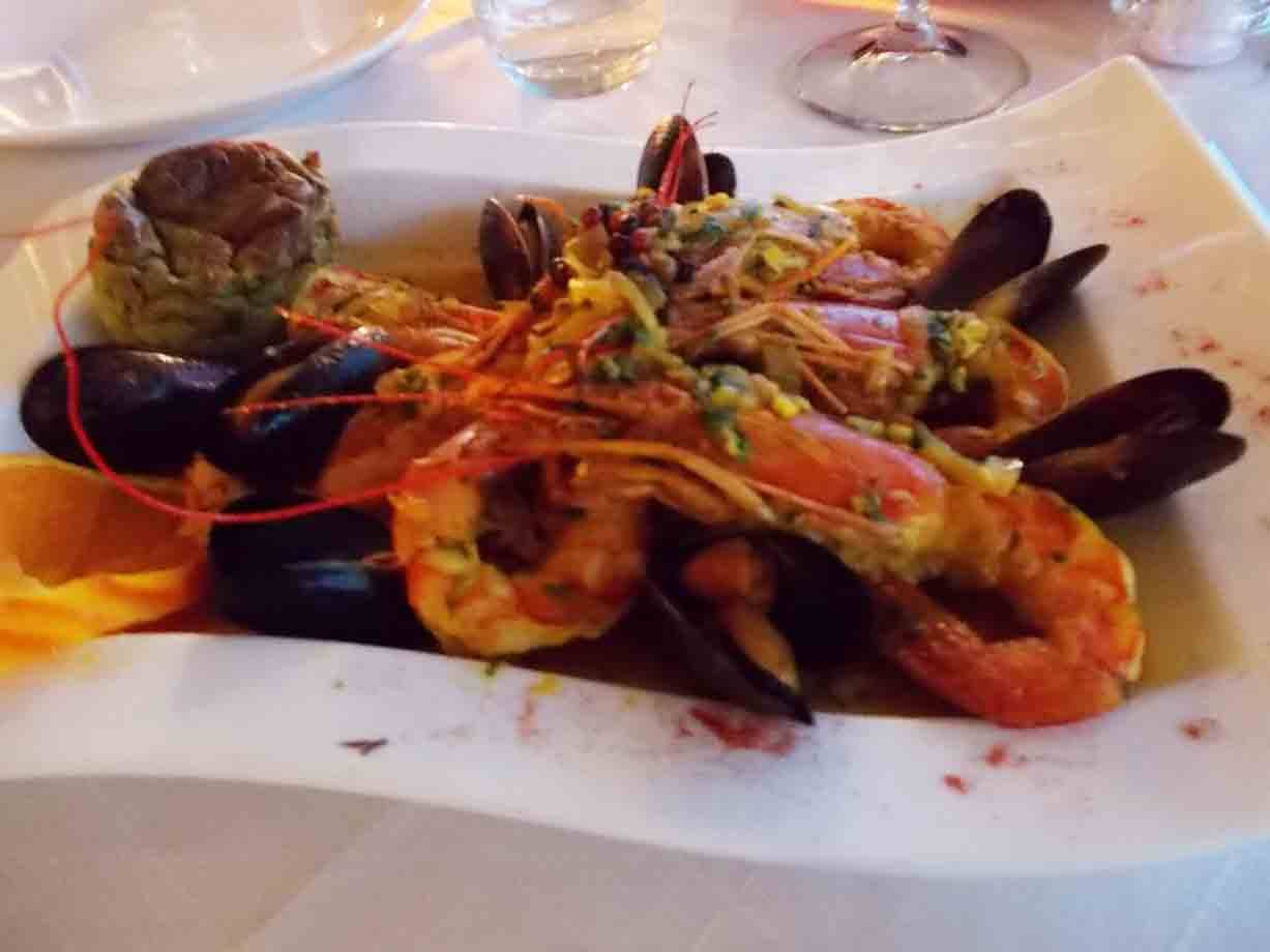 Piatti di gamberi e cozze in salsa, serviti su piatto bianco in ristorante
