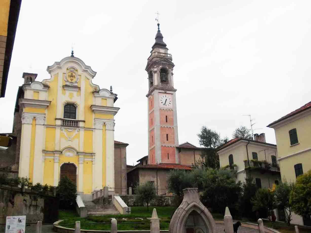 Chiesa barocca gialla con campanile rossastro e orologio, cielo grigio