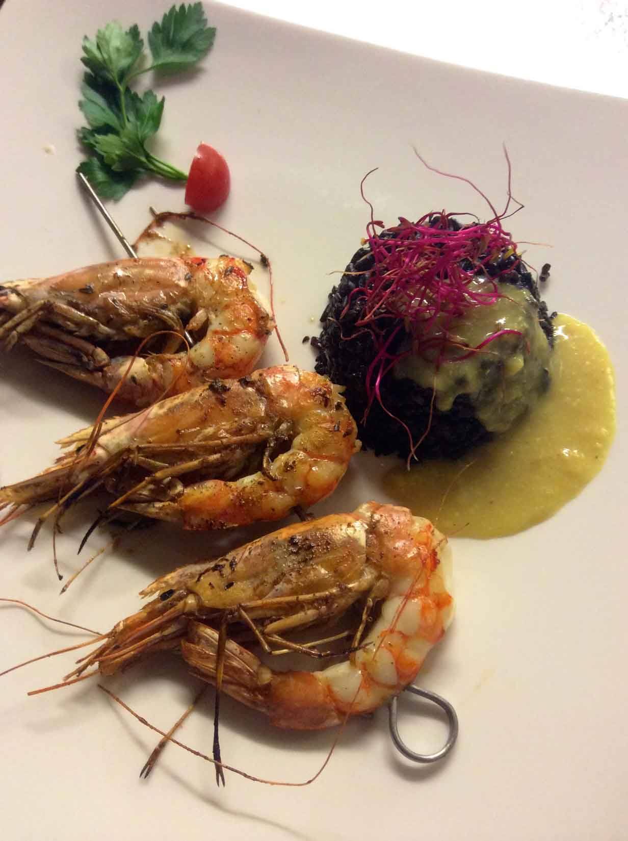 Gamberi arrosto su spiedino con riso al nero di seppia e salsa gialla