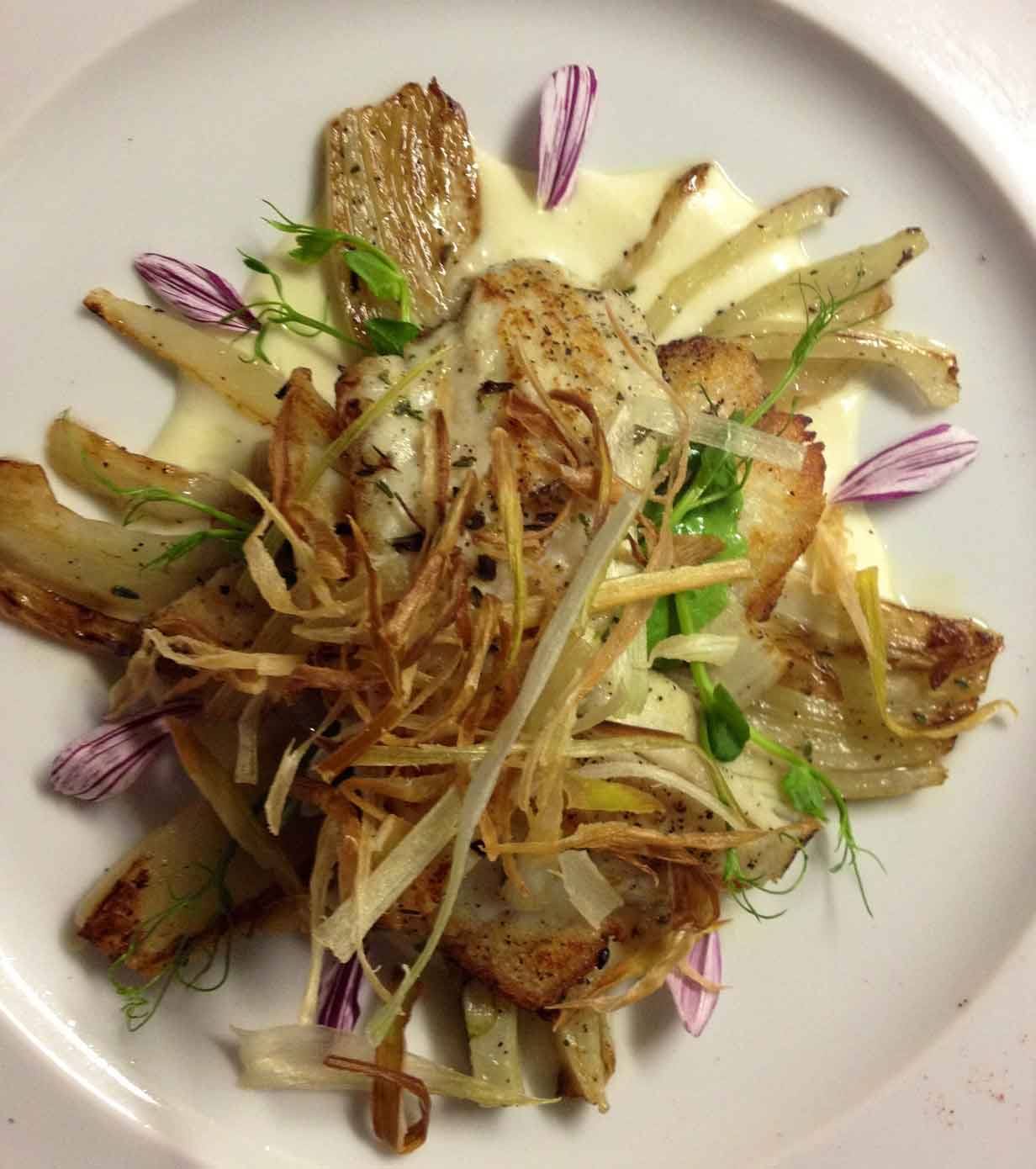 Piatto gourmet con carciofi arrosto, scaglie croccanti, crema e fiori viola