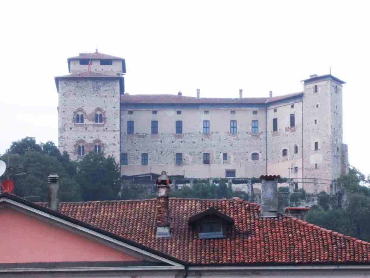 Castello in pietra con torri sopra i tetti di coppi rossi, luce grigia